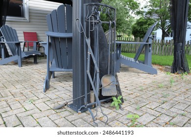 rusty fire pit tools in front of patio furniture on a brick deck