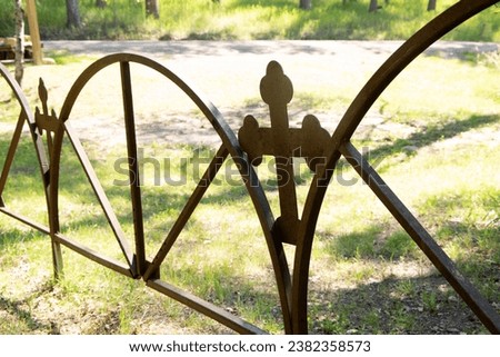 rusty gate with a cross design with green grass and sunlight on a bright sunny day like from a cemetery or church  