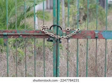 Rusty gate with locked master key and chain.