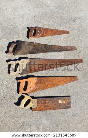 Rusty hand saws on a patch of concrete