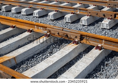 Rusty intermediate rail fasteners on concrete sleepers for train and tram, laying railroad tracks