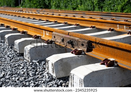 Rusty intermediate rail fasteners on concrete sleepers for train and tram, laying railroad tracks
