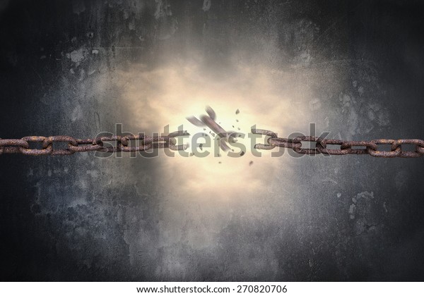 Rusty iron chains broken with\
red bright spark light on dark mottled concrete wall\
background