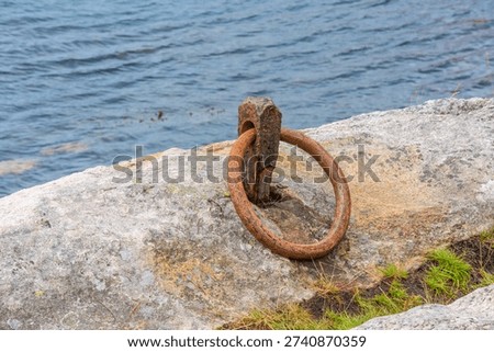 Rusty iron mooring ring fixed in coastal rock