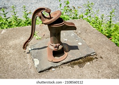 Rusty Manual Water Pump on Stone Well Cap with Moss