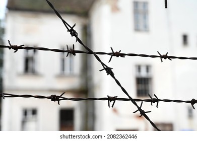 Rusty metal barbered wire on former concentration camp. Wire fence near old military barracks. Close up of barber wire near jail or prison.
