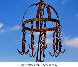 Rusty metal hanging hooks and chains against a blue sky