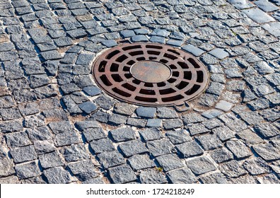Rusty metal manhole cover on urban pavement road. Round drainage sewer manhole
