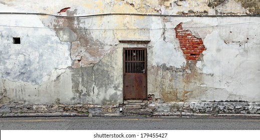 A Rusty Metal Old Backdoor On A Dilapidated Grungy Brick Wall In A Back Alley.  