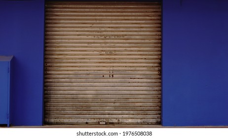 Rusty Metal Rolling Door On Blue Facade