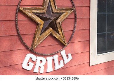 Rusty Metal Star Sign Hanging On A  Red Wooden Wall Of A Grill Place In Houston, Texas