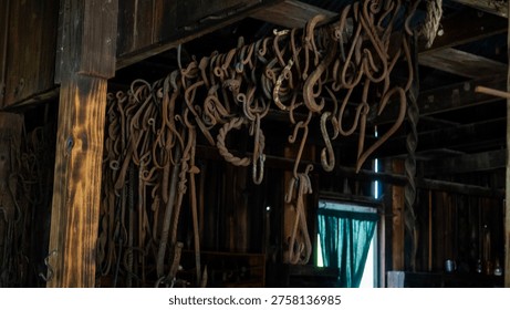 Rusty metal tools hanging inside old wooden barn with window light