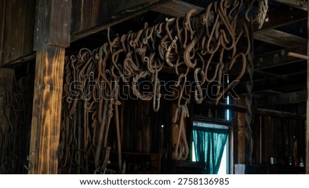 Rusty metal tools hanging inside old wooden barn with window light