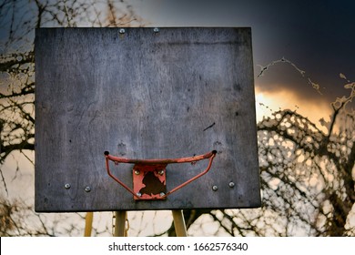 rusty old basketball hoop against a sky in the evening