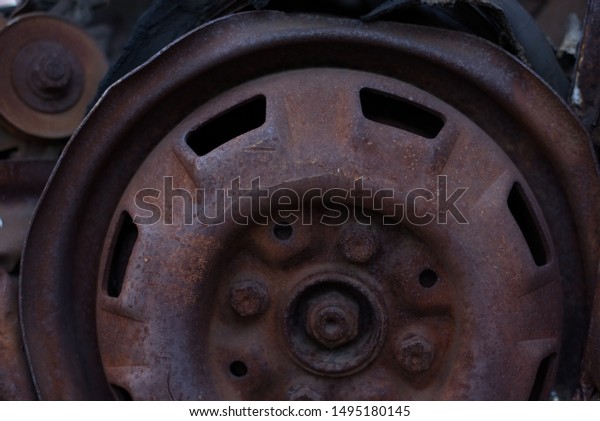Rusty old car wheel\
(automobile) rusting in a scrapyard. Car auto parts background\
texture detail