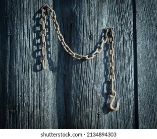 A Rusty Old Farm Tractor Chain Hangs  From A Pine Barn-board Shed