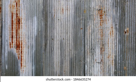 Rusty old galvanized fence. The background and texture of the broken and dirty silver wavy metal lines fill the frame rate. wallpaper for design work with copy space. select focus