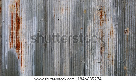 Rusty old galvanized fence. The background and texture of the broken and dirty silver wavy metal lines fill the frame rate. wallpaper for design work with copy space. select focus