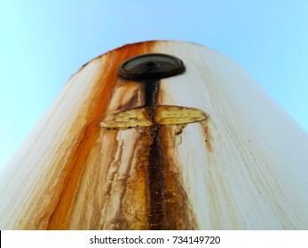 A Rusty And Old Leaking Water Heater On The Roof With Blue Sky On The Background