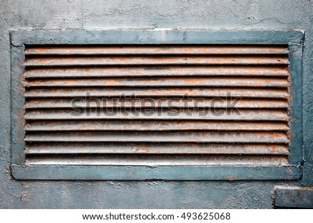 Rusty old ventilation grille on metal wall painted in blue