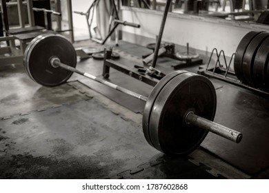 A rusty olympic size barbell loaded with plates on rubber matting. In position for deadlift. hardcore theme and setting.