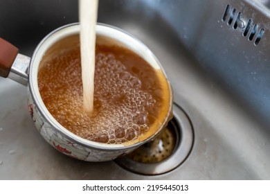 Rusty Orange Water Flows From The Kitchen Faucet Into The Pot.