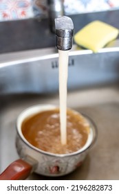 Rusty Orange Water Flows From The Kitchen Faucet Into The Pot.