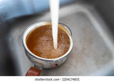 Rusty Orange Water Flows From The Kitchen Faucet Into The Pot.