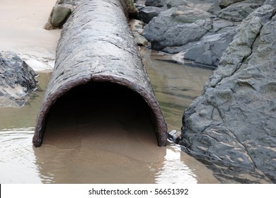 a rusty overflow pipe coming from the land to the sea