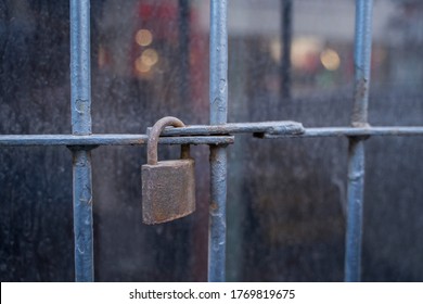 Rusty Padlock Hanging From A Metal Bar On The Entrance To A Closed Shop