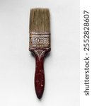 Rusty Paintbrush on White Background. A close-up image of an old, weathered paintbrush with a rusted metal ferrule and a dark brown handle, marked with 