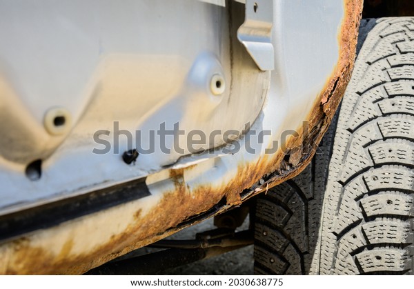 Rusty part of the car body\
with through-out corrosion. Background for cars requiring body\
repair
