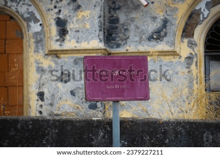 Rusty and peeling iron sign, purple in color with the writing VECCHIO FARO SECOLO XX (1911) which means old lighthouse, twentieth century (1911)