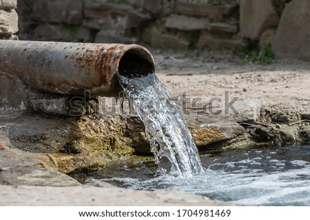 rusty pipe with flowing water into the river