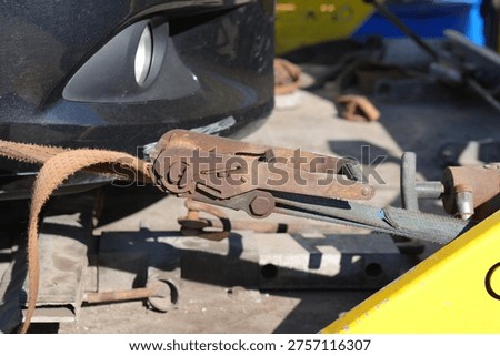 Rusty Ratchet Strap Securing Car to Tow Truck Recovery Platform