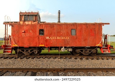 Rusty Red Rail Car. An old train car sit abandoned on display in a small town. Yellow railroad painted on the sign as it sits idle on the tracks. A historic piece of transport and old time frieght - Powered by Shutterstock