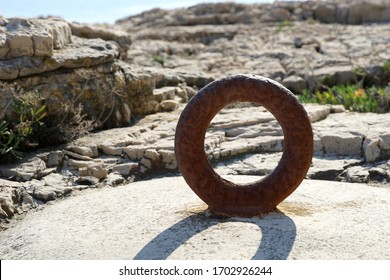 Rusty ring on the stone by the sea in the noon sun. Old vintage metal ring for mooring sea boat
