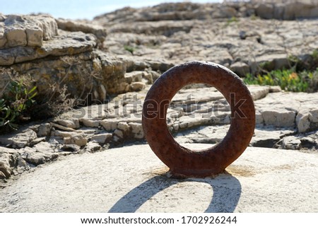 Rusty ring on the stone by the sea in the noon sun. Old vintage metal ring for mooring sea boat