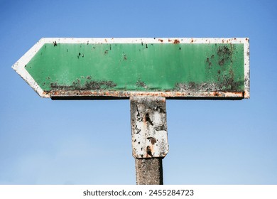 Rusty road sign arrow. Green direction indicator. Empty blank copy space. Traffic sign isolated on blue sky. Orange rust and dirt. Concrete pole old style sign. - Powered by Shutterstock