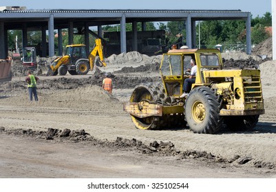 Rusty roll compactor working on sand area at construction site