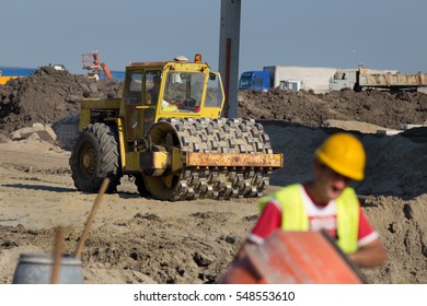 Rusty roll compactor working on sand area at construction site