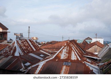 Rusty Rooftops Of A Small Town Marked By Weathered Metal Roofs At Dusk