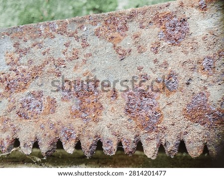 Rusty saw blade with large corroded spots and dusty gray texture