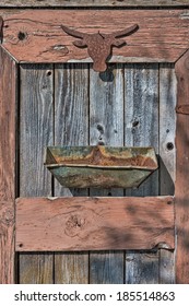 The Rusty Silhouette Of A Western Steer Head Is Nailed To The Weathered Door Of A Shed With A Rusted Out Metal Container Nailed Below It In An Artistic Garden Art Collage.