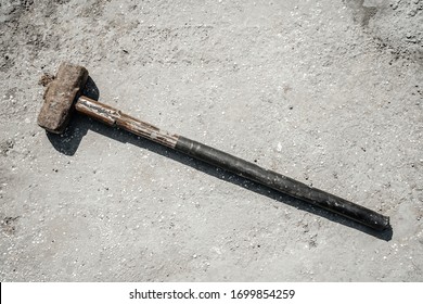 Rusty sledgehammer on concrete slab and concrete stones. Metal sledgehammer.
