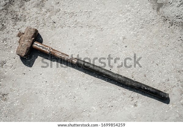 Rusty sledgehammer on concrete slab and\
concrete stones. Metal\
sledgehammer.
