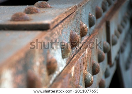 Rusty steel girders with rivets on a railway bridge