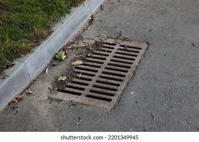 Rusty Storm Drain Grate On The Road Next To The Lawn