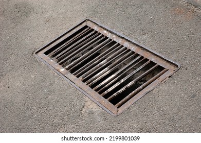 A Rusty Storm Grate In An Asphalt Road