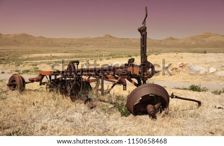Rusty tractor trailer part in the middle of prairies